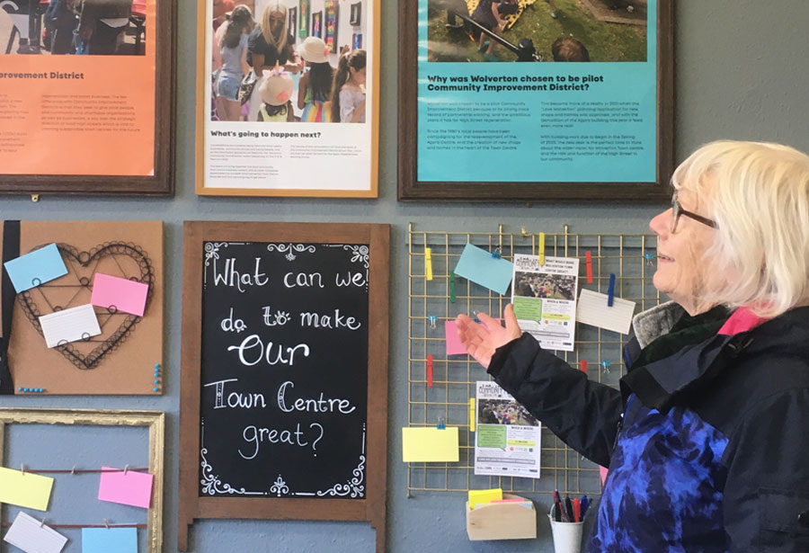 A member of Still Green Cohousing looking at a colourful community noticeboard in Wolverton